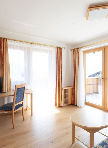 Living room with desk, TV, and balcony in the Hirzer Suite